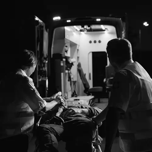 A man being carried into an ambulance with two rescue workers giving him oxygen