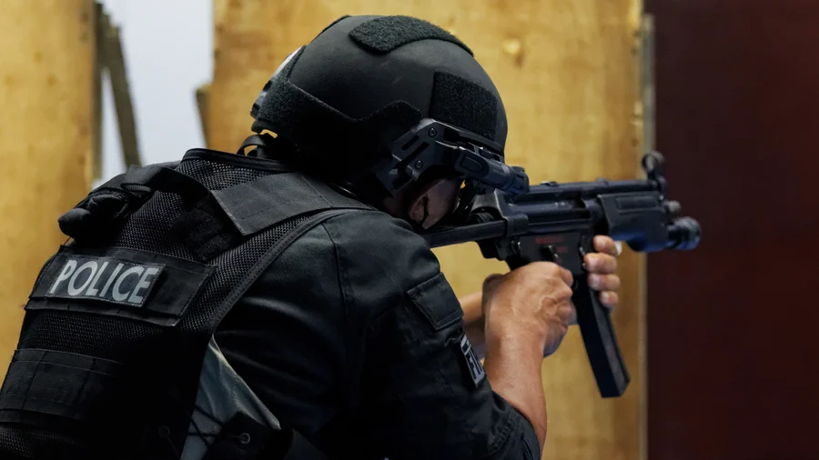 A police officer wearing a bulletproof helmet training with an MP5 submachine gun