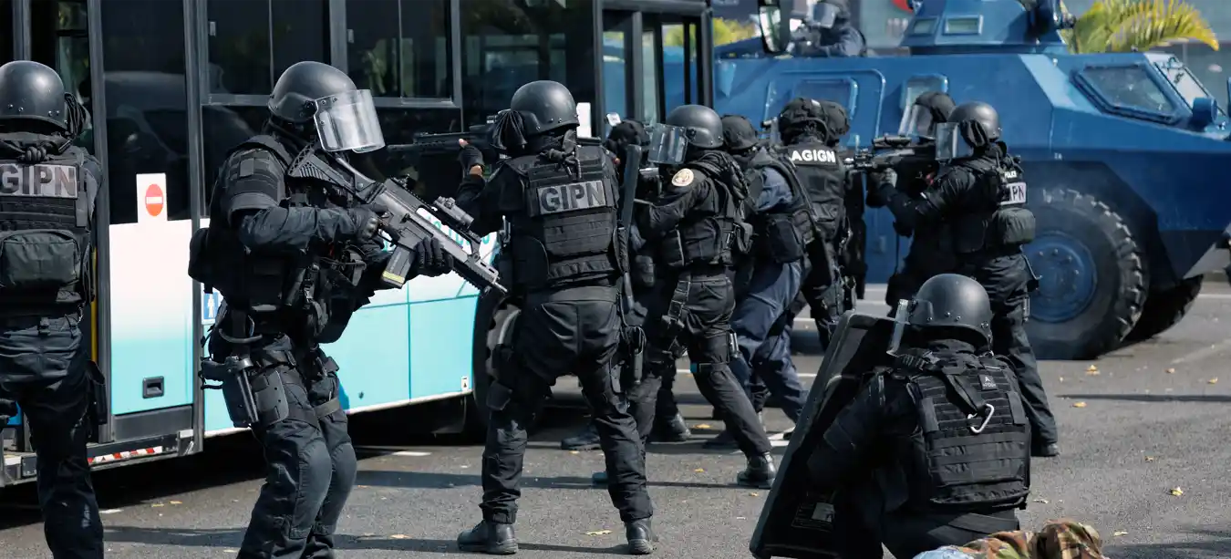 Multiple heavily armed police officers pointing their weapons at a bus during counter-terror training